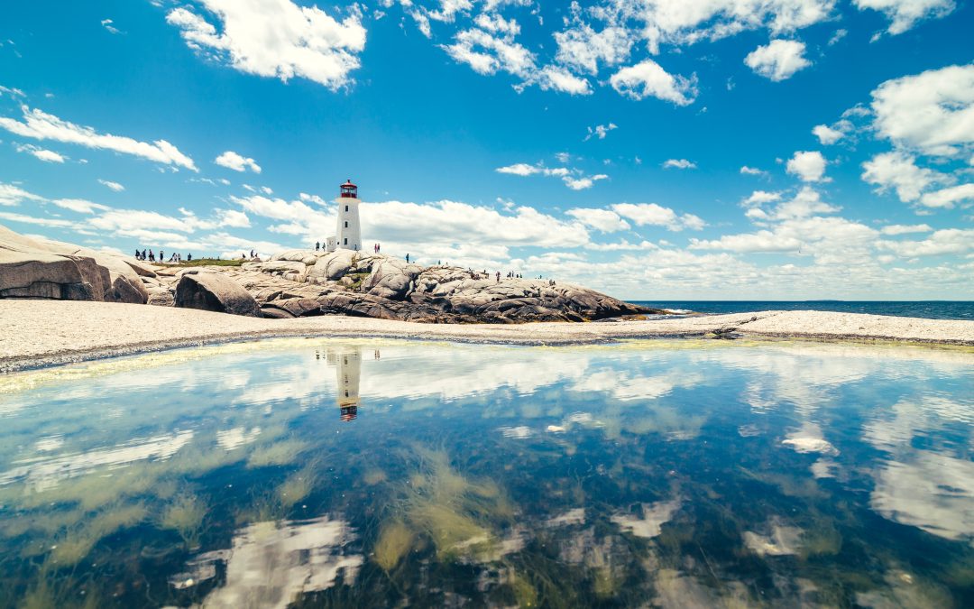 lighthouse tower near calm water under white clouds and blue sky