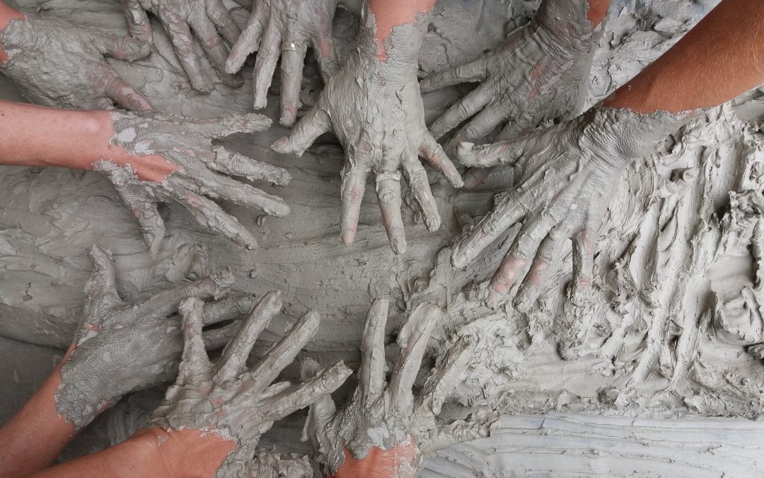 people's hand on gray mud