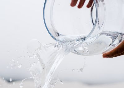 person holding clear glass jar with water