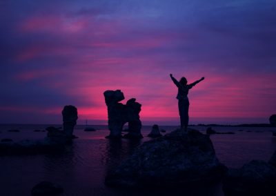 person standing on rock formation with arms in air