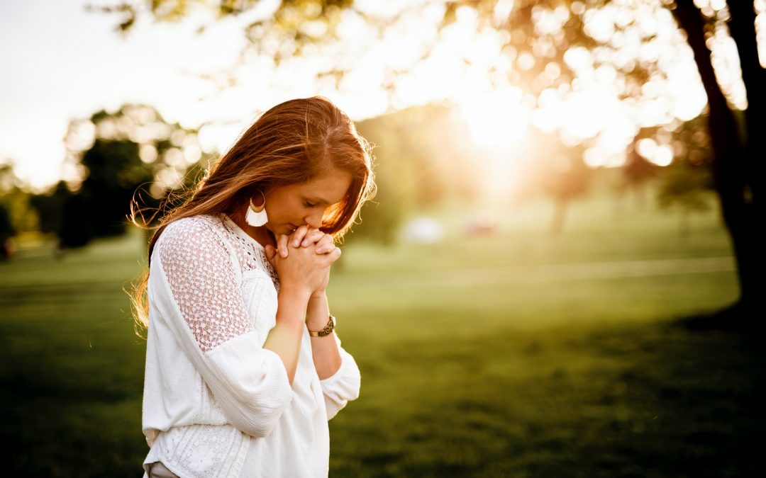 woman praying beside tree