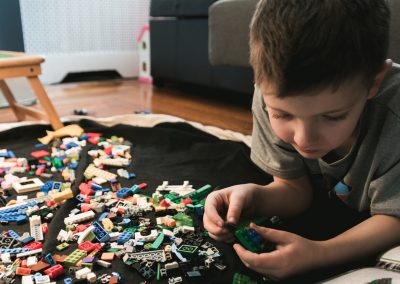 boy in grey crew-neck t-shirt plays LEGO bricks with white manual book