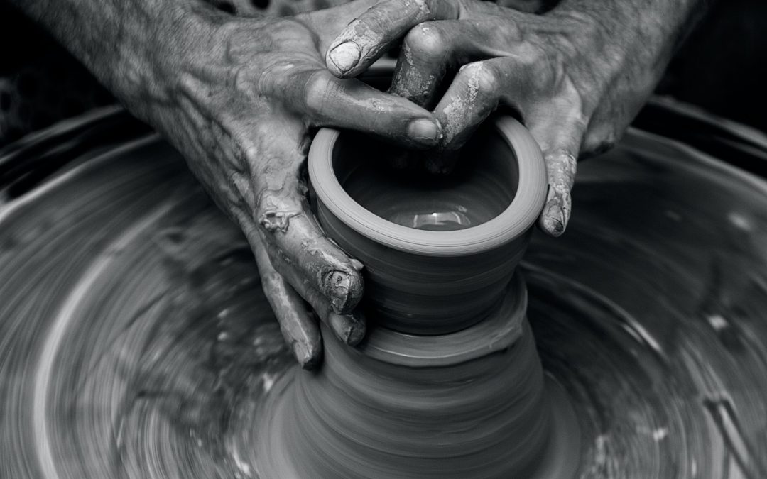 Messy hands sculpting on a pottery wheel in motion