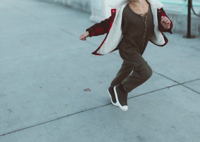 woman in black jacket and white pants sitting on concrete floor during daytime