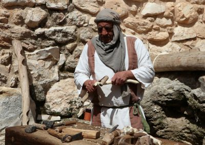 man in white long sleeve shirt and blue pants holding brown wooden stick