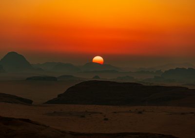 the sun is setting over the mountains in the desert
