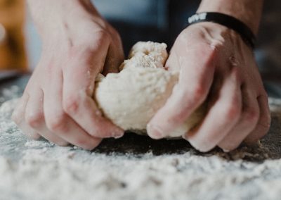 person holding white dough on brown wooden table