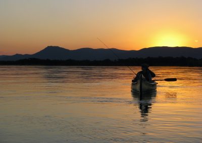 a person in a kayak on a lake at sunset