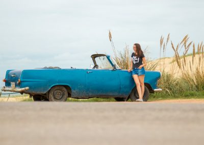 woman leaning on blue convertible coupe