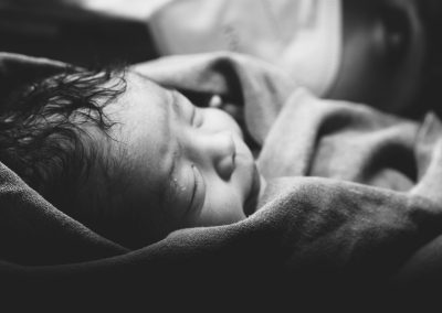a black and white photo of a baby wrapped in a blanket