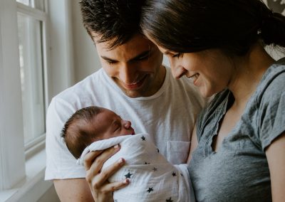 woman holding baby beside man smiling