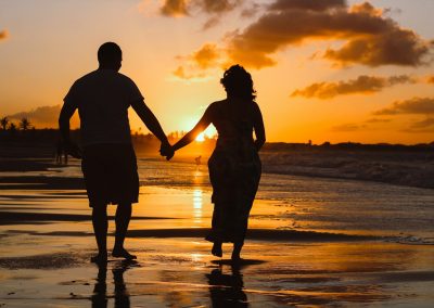 couple standing on body of water during golden hour