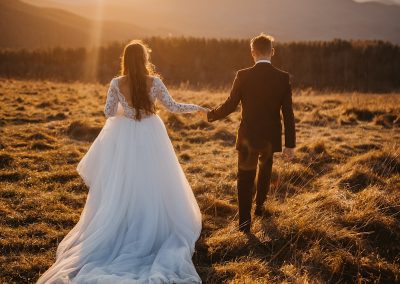 man and woman in wedding dress walking on brown grass field during daytime