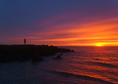 a person standing on the edge of a cliff at sunset